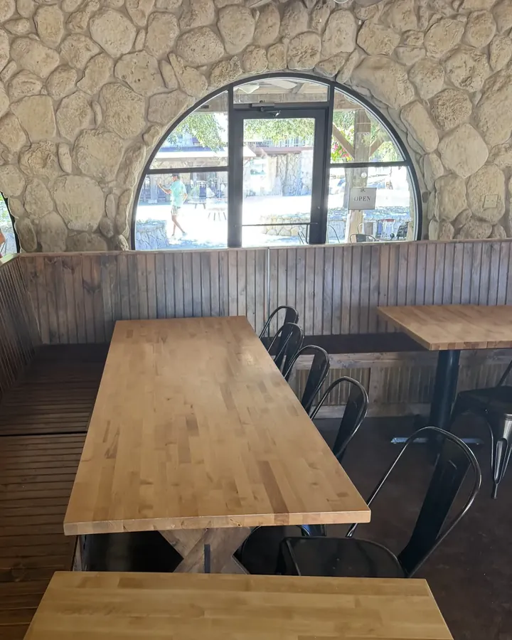 Seating in the coffee & tea bar at LoneHollow Ranch, Texas: butcher-block tables beneath an arched window in a stone wall